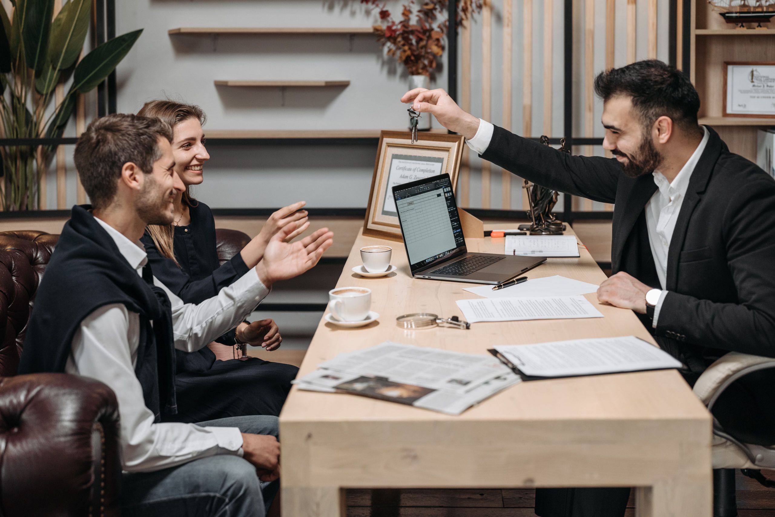 Professionnel remet clés aux clients souriants lors consultation